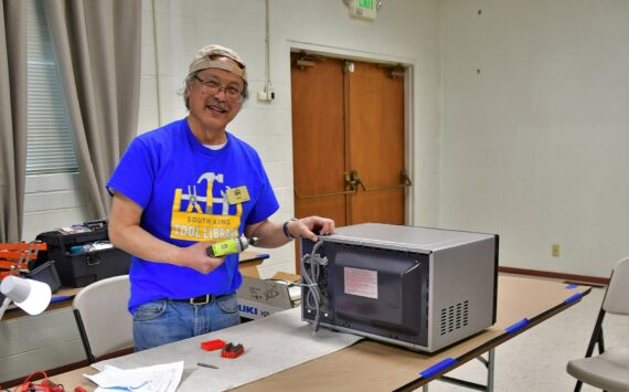 Gary Ichinaga, a volunteer fixer at the South King Tool Library, works on a microwave during last week’s repair cafe, an event in which locals can get help repairing their stuff rather than throwing it away. Photo by Bruce Honda.