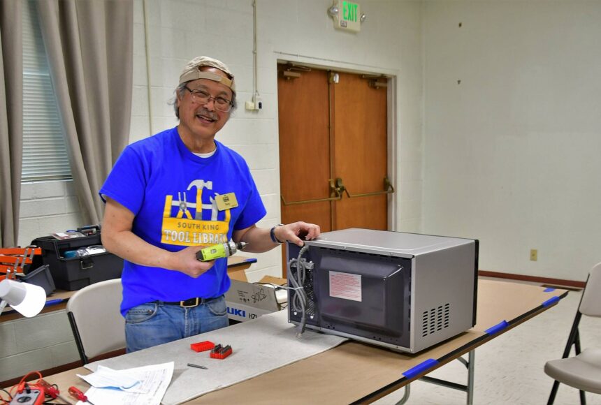 <p>Gary Ichinaga, a volunteer fixer at the South King Tool Library, works on a microwave during last week’s repair cafe, an event in which locals can get help repairing their stuff rather than throwing it away. Photo by Bruce Honda.</p>