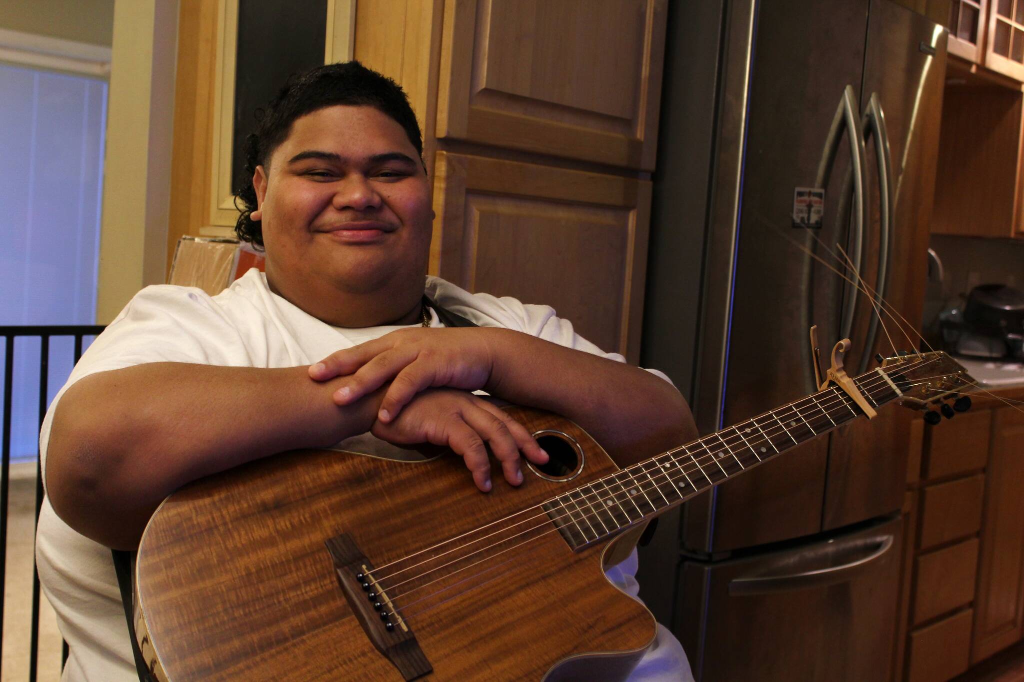 Alex Bruell / The Mirror
Decatur High School senior and “American Idol” contestant Iam Tongi sits at home on March 1. His father Rodney spent a bonus from his job as an electrician to buy Iam’s guitar.