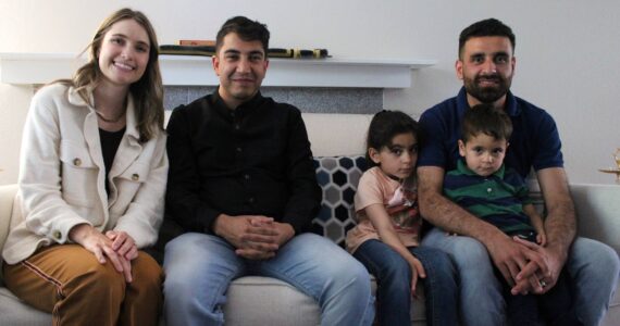 Left to right: Heather Brandt, program manager for refugee and immigrant services at Lutheran Community Services Northwest; Ghulamfarooq Noorzai, case manager for the Stanikzai family, and Hamid Stanikzai, along with two of his children, pose for a picture at his Federal Way area home. (Photo by Alex Bruell / The Mirror)