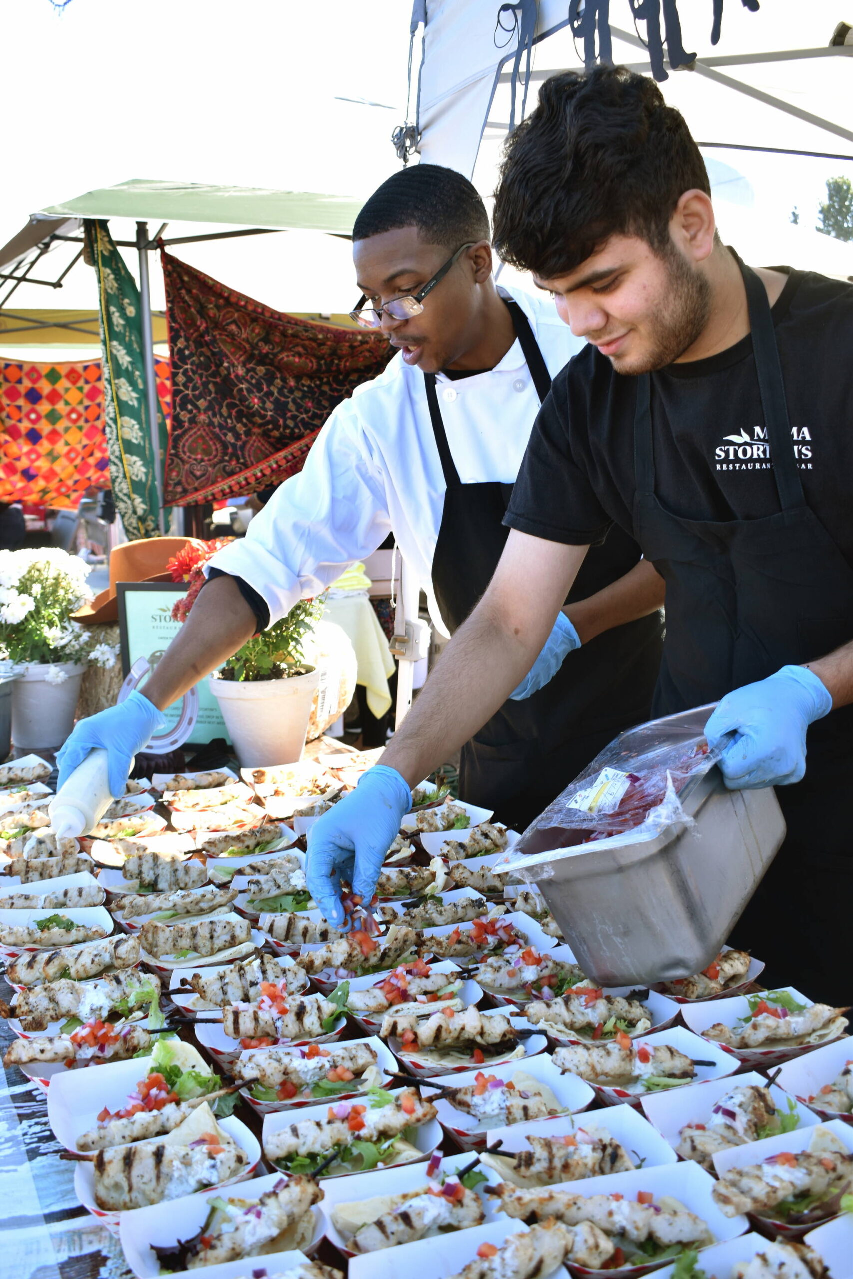 Hassan Obabunmi, left, and Masih Rahmani prepare marinated chicken skewers for Mama Stortini’s entry at the Taste of Federal Way in 2022. File photo.