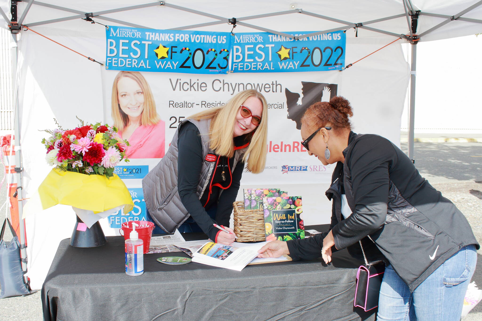 Local Realtor Pauline Jones gets her copy of Vickie Chynoweth’s new cookbook signed at the Federal Way Farmers Market on Saturday. Photo by Keelin Everly-Lang / The Mirror