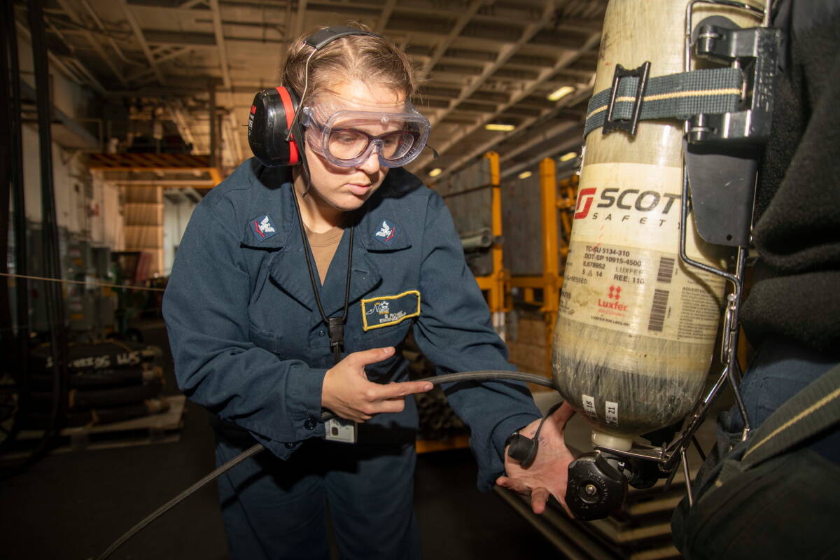 U.S. Navy photo by Mass Communication Specialist 2nd Class Caylen McCutcheon
U.S. Navy Damage Controlman 3rd Class Stephanie Rowe, from Federal Way, Washington, refills SCBA bottles following a firefighting drill aboard the aircraft carrier USS Nimitz (CVN 68) while in port at Naval Base Kitsap-Bremerton, Washington, Oct. 18, 2023. Nimitz is in port conducting routine operations. (This photo has been altered for security purposes by blurring out security badges.)