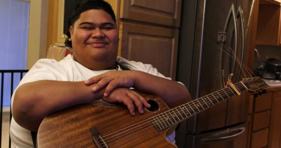 Decatur High School senior and “American Idol” contestant Iam Tongi sits at home on March 1. His father Rodney spent a bonus from his job as an electrician to buy Iam’s guitar. Tongi went on to win this year’s season of “American Idol.” (Alex Bruell / The Mirror)