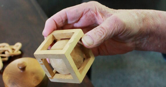 Artist Dick Ode said he has enjoyed working with wood since he was a young, and used it as a way to pass the time while traveling for work. This wooden ball and cube were whittled at the same time from the same solid block. Photo by Keelin Everly-Lang / The Mirror