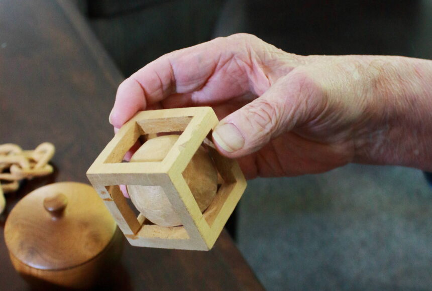 <p>Artist Dick Ode said he has enjoyed working with wood since he was a young, and used it as a way to pass the time while traveling for work. This wooden ball and cube were whittled at the same time from the same solid block. Photo by Keelin Everly-Lang / The Mirror</p>