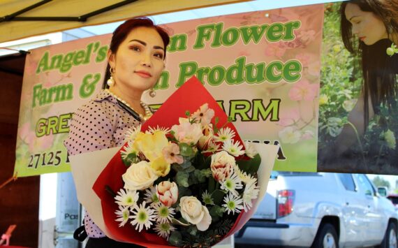 Angel Vue shows off one of the flower bouquets for sale at her storefront at last year’s Federal Way Farmers Market. File photo