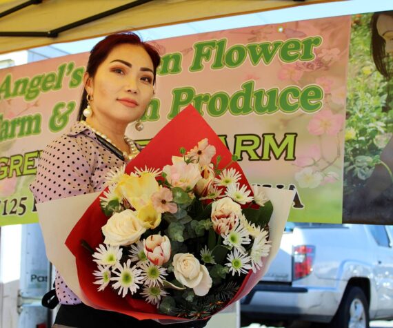 Angel Vue shows off one of the flower bouquets for sale at her storefront at last year’s Federal Way Farmers Market. File photo
