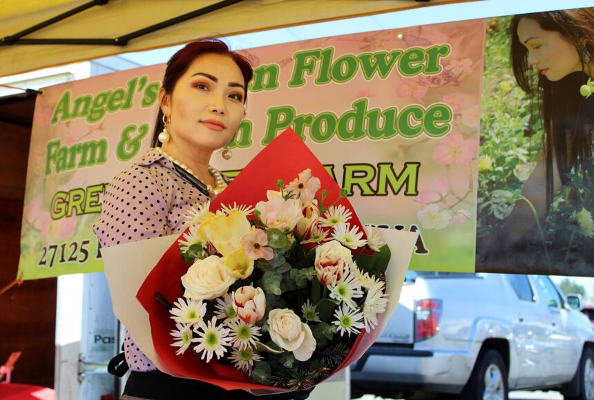 <p>Angel Vue shows off one of the flower bouquets for sale at her storefront at last year’s Federal Way Farmers Market. File photo</p>