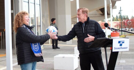 King County Councilmember Pete von Reichbauer hands a soccer ball to Auburn Mayor Nancy Backus at a press event at the Federal Way transit station on Oct. 30 to kick off simulated service of the new Federal Way Link Extension. For the next month, the trains will run their regular schedule without passengers to ensure the trains are ready to go live starting Dec. 6. Photo by Keelin Everly-Lang / the Mirror