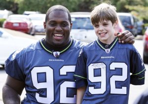 Nautilus Elementary School fourth-grader Alex Bradshaw poses with Seattle Seahawks defensive lineman Brandon Mebane Tuesday at the school. Mebane granted Bradshaw’s wish for Seahawks season tickets by paying for four sets for Bradshaw and his family. Bradshaw suffers from Ogilvie syndrome and went into cardiac arrest on Feb. 14.