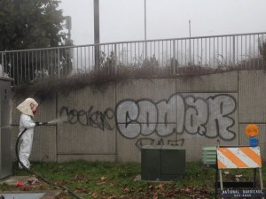 A city of Federal Way employee uses a sand blasting machine to remove graffiti from public property.