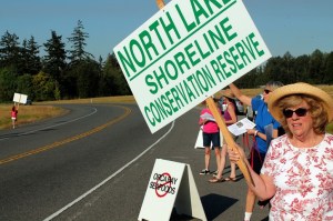 Residents from nearby neighborhoods wave signs and hand out information sheets across the street from the former Weyerhaeuser building