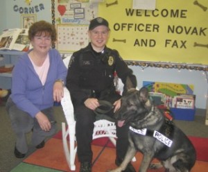 Lake Dolloff Elementary kindergarten teacher Jeanne Epp poses in her classroom with Federal Way police officer Matt Novak and K-9 officer Fax. Epp's students donated money they earned by doing chores to help buy Fax a ballistic vest.