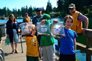 Three boys hold up fish at the annual Hooked on Fishing event at Steel Lake on Saturday