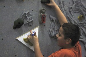 Lake Dolloff Elementary students have to hang onto the rock wall while solving math problems written on the whiteboards spaced along the wall.