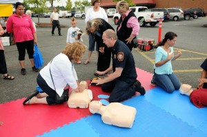 South King Fire and Rescue Lt. Jeff Bellinghausen teaches a woman how to perform CPR on a dummy during the annual Federal Way Farmers Market Family Safety Day on Saturday. This was the first year the department offered free CPR training.