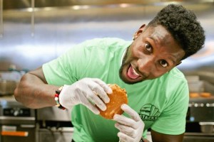 Former Seahawks cornerback Marcus Trufant bites into a custom burger he built  to benefit the Trufant Family Foundation on Thursday at Stacks in Federal Way.