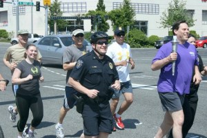 Federal Way Mayor Jim Ferrell (right) carries a torch and leads a group of Federal Way police officers and officials with Homeland Security's Federal Protective Service along Pacific Highway South