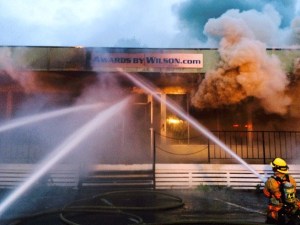 Firefighters from South King Fire and Rescue extinguish flames at Awards By Wilson and other neighboring businesses in the strip mall along Pacific Highway South on Tuesday morning.