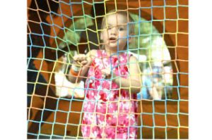 Two-year-old Kayleigh McIntyre holds on to the sides of an inflatable attraction Aug. 6 during Kids Day at Steel Lake Park while older children bounce around behind her.