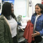 Annette Acheampong, 16, left, and Sarah Jacob, 16, both juniors at the Technology Access Foundation Academy, talk about their plans to complete their clothing line using colorful fabric with different designs at the school recently. The students, along with Cecilia Jacobs, not pictured, created the clothing design company Melan, which aims to empower women of color by featuring clothes that flatters their skin tone. JESSICA KELLER, the Mirror