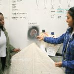 Technology Access Foundation Academy juniors Annette Acheampong, left, and Sarah Jacob, both from Federal Way, talk about the pookalam design, which features elaborate flowers, Jacob wants to incorporate in the clothing she will contribute to their fashion show, which will take place in April. The clothes, which is meant to flatter and appeal to women of color, will all incorporate aspects of the students&rsquo; ethnic backgrounds. Jessica Keller photo
