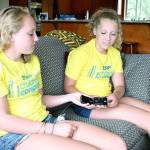 Federal Way sisters Evie, left, and Lilly Tucker show the continuous glucose monitoring systems that tracks their blood sugar levels and reports the results to apps on their phones. The teens, who attend Decatur High School, were diagnosed with diabetes as children and manage their illnesses while maintaining regular lifestyles. Jessica Keller, the Mirror