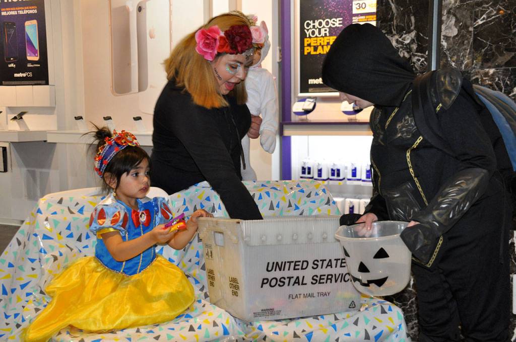 Fatima El Moussa, 3, left, and Maggy Lopez, 14, hand out candy to trick-or-treaters at The Commons on Tuesday night. HEIDI SANDERS, the Mirror