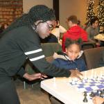 Phiona Mutesi, an international chess champion from Uganda who was depicted in a movie Queen of Katwe, helps 10-year-old Thalia Smith arrange the chess board as 13-year-old Samantha Valenzuela looks on during a Chess with the Superintendent session Wednesday at Family Life Community Church. The youth, most of whom are students in Federal Way, received a basic lesson from Superintendent Tammy Campbell, while Mutesi walked around offering pointers to students. The students left with a chess board of their own. JESSICA KELLER, the Mirror