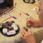Leora Kuwitzky, 88, uses a paint pen to write the names of her grandchildren on rocks during the Federal Way Rocks event at Brookdale Foundation House. This event helped bring older and younger generations closer together. Courtesy Miasmin Andre, UW News Lab