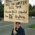 Jack Sharlock waved a sign Wednesday at the corner of South 320th Street and First Avenue to protest a proposed utility tax in Federal Way. ANDY HOBBS, the Mirror