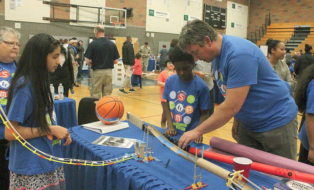 Rainier Elementary School fifth-grade teacher Glyn Jenkins and a couple of his students assemble the different pieces of their Rube Goldberg Machine they tested at the FWPS second annual STEM Exploration Night Wednesday, March 28, at Todd Beamer High School. Jessica Keller, the Mirrror