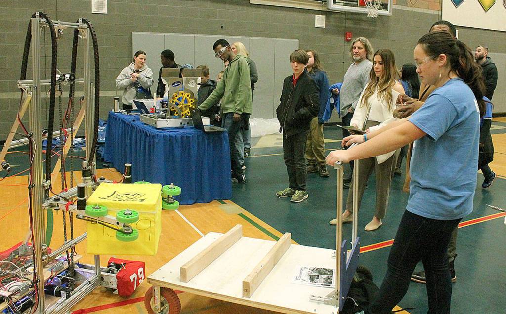 Federal Way High School sophomore Meghan Kon, a member of the RoboEagles robotics team, holds a flatbed dolly still while other RoboEagles help younger students maneuver the robot and block with a joy stick at the FWPS STEM Exploration Night, Wednesday, March 28, at Todd Beamer High School. Jessica Keller, the Mirror