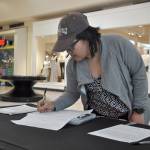 Socheatey Cheng, of Federal Way, signs a petition requesting a recently passed utility tax be brought to a vote of residents at The Commons mall on Tuesday afternoon. HEIDI JACOBS, the Mirror