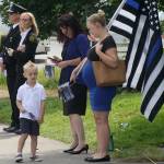 A woman brings a large flag and small flags as she watches the procession Tuesday for Kent Police Officer Diego Moreno along West James Street. STEVE HUNTER, Kent Reporter