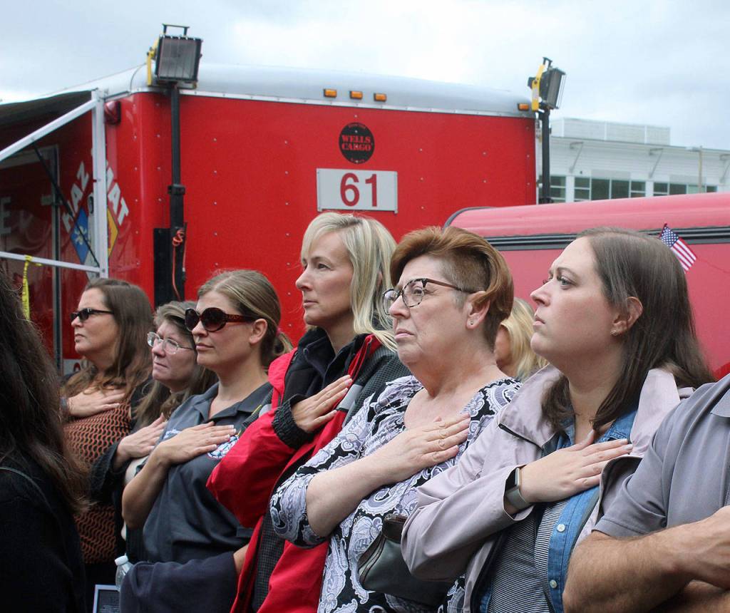 Community members put their hands over their hearts as the South King Fire and Rescue Honor Guard raises the flag. Olivia Sullivan/staff photo