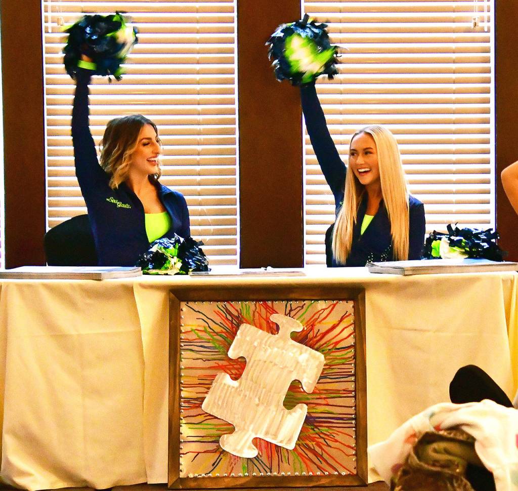 Two of the Sea Gals also attended the event to show support, meeting fans and signing posters. The art piece in front was auctioned off for more than $200. Photo courtesy of Bruce Honda