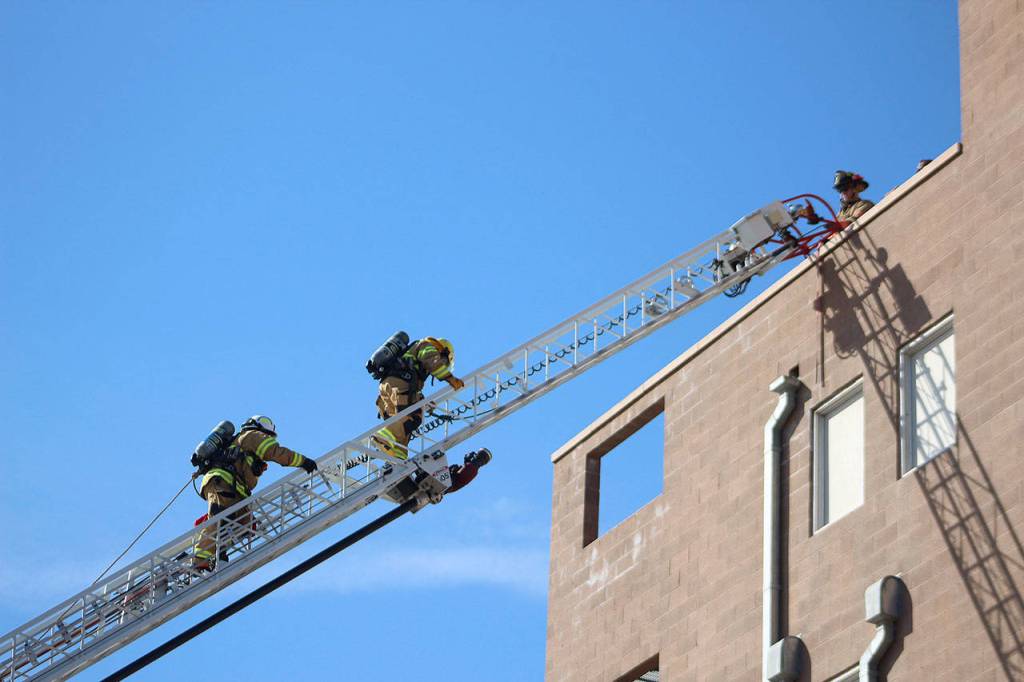 An attendee and their shadow near the top of an engine ladder at Fire Ops 101. Olivia Sullivan/staff photo
