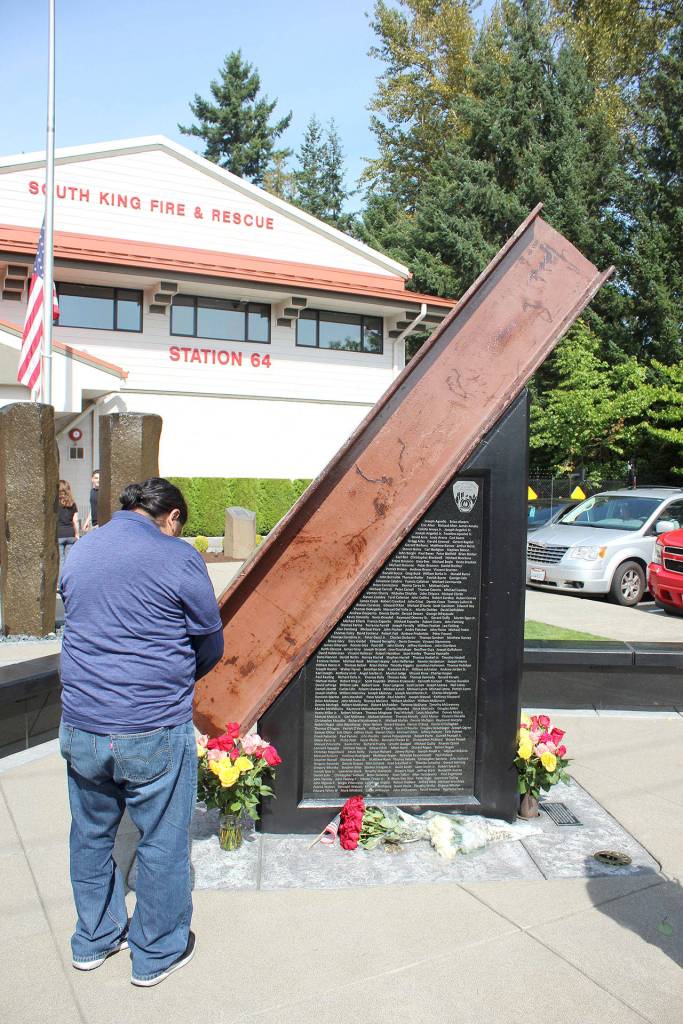 A person prays before a 10-foot steel beam from the wreckage of the World Trade Center in New York, which is part of the South King Fire and Rescues memorial honoring the lives lost in the Sept. 11, 2001 terrorist attacks. Olivia Sullivan/staff photo