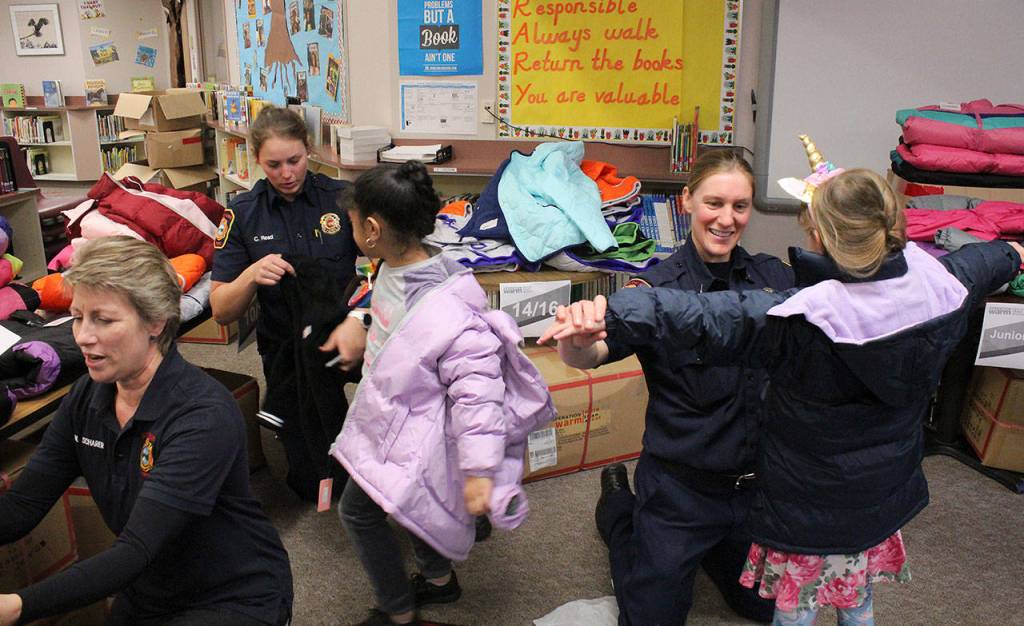 Marilyn Schrarer, left, firefighter Chloe Reed, and Lt. Shannon Oltman help students at Rainier View find the perfect fit of winter coats at Operation Warm. Olivia Sullivan/staff photo