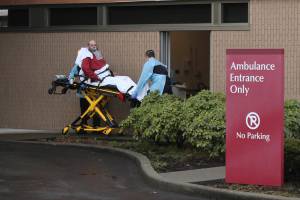 At St. Elizabeth Hospital in Enumclaw, a patient is taken from an ambulance through a small door marked decontamination on March 23. It was unclear whether the patient was suspected of being infected with COVID-19. (Photo by Ray Miller-Still/Sound Publishing)