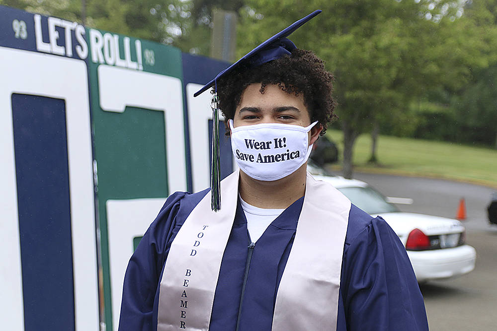 Senior Tayshon Cottrell dons his graduation cap and gown, along with a face mask reading: Wear it! Save America at Todd Beamer High Schools virtual graduation walk recording on May 20 in Federal Way. Olivia Sullivan/staff photo