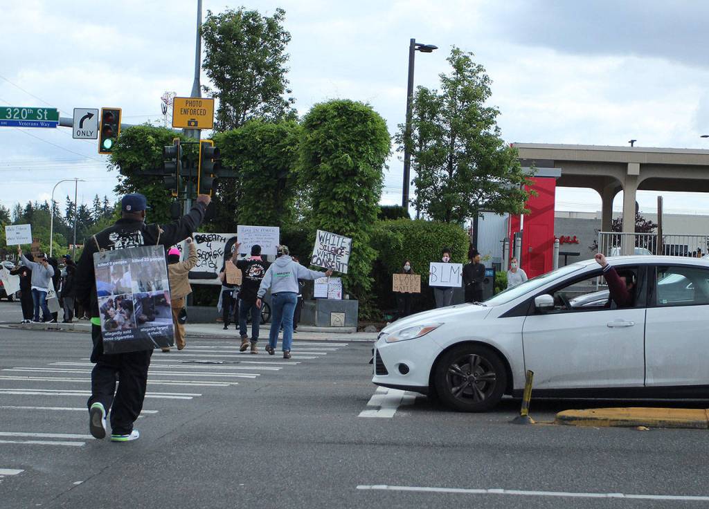 A man in his car stopped at the intersection raises his fist in solidarity with a protester crossing the street on Sunday, May 31. Olivia Sullivan/staff photo