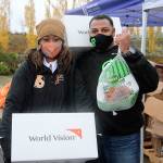 World Vision Corporate Engagement Director Samantha King, left, and Chip-in Founder Gerald Smiley pause for a photo while providing turkeys, fresh food kits, PPE and school supplies to more than 300 local families at Federal Way High School on Nov. 23. Olivia Sullivan/the Mirror