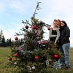 Lori Allen, right, stands near the Federal Way community Christmas tree located near S. 336th Street near the former Weyerhaeuser campus with her daughter Savannah, left, and husband Jeff, back, on Dec. 10. Photo by Andy Hobbs