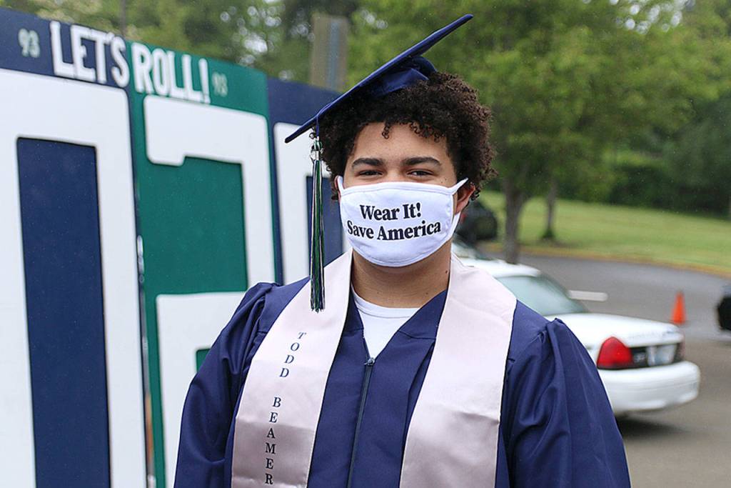 Senior Tayshon Cottrell dons his graduation cap and gown, along with a face mask reading: Wear it! Save America at Todd Beamer High Schools virtual graduation walk recording on May 20 in Federal Way. Olivia Sullivan/staff photo