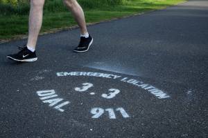 A man walks past an emergency location mile marker along the BPA Trail at dusk on May 11. Olivia Sullivan/the Mirror