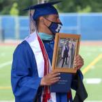 Federal Way football coach Marcus Yzaguirre holds a photo of 17-year-old Damoni Nelson after receiving a diploma on his behalf on June 10. Damoni, a well-loved star athlete and student at Federal Way, was fatally shot in Oct. 2020. Olivia Sullivan/the Mirror