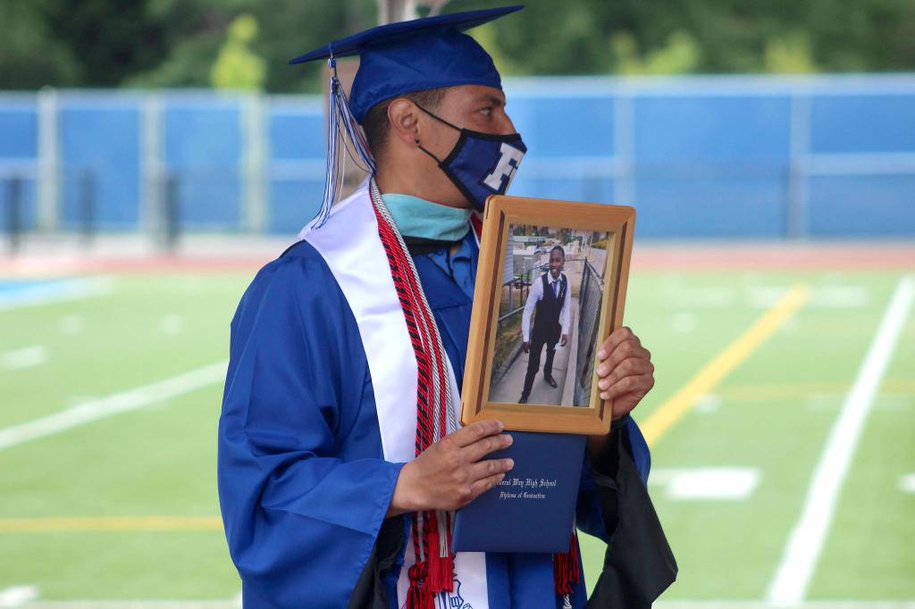 Federal Way football coach Marcus Yzaguirre holds a photo of 17-year-old Damoni Nelson after receiving a diploma on his behalf on June 10. Damoni, a well-loved star athlete and student at Federal Way, was fatally shot in Oct. 2020. Olivia Sullivan/the Mirror